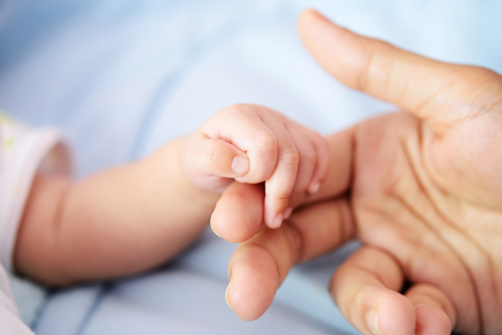 Newborn hand touching mother's hand